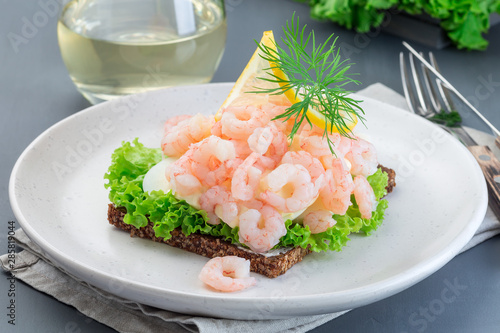 Traditional savory swedish sandwich with a dark bread, lettuce, eggs, mayonnaise, shrimps, dill and lemon, horizontal