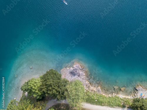 Up and down drone aerial view of the lake Ledro. A natural alpine lake. Amazing turquoise, green and blue natural colors. Italian Alps. Italy. Touristic destination. Summer time