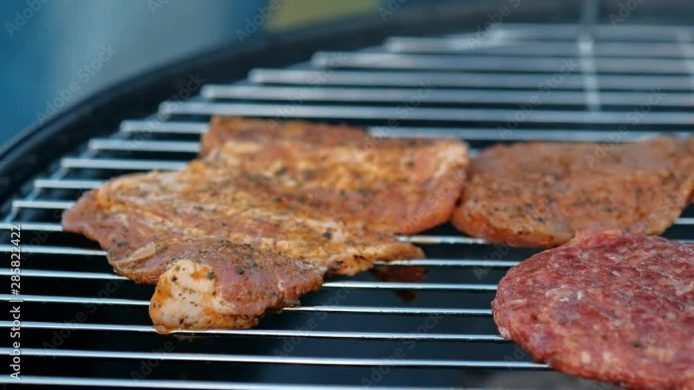 Barbecue grill. A man fries meat steaks and meatballs for hamburgers, turns the meat over with tongs. The concept of cooking meat outdoor. Barbecue grill. A man fries meat steaks and meatballs for hamburgers, turns the meat over with tongs. The concept of cooking meat outdoor.