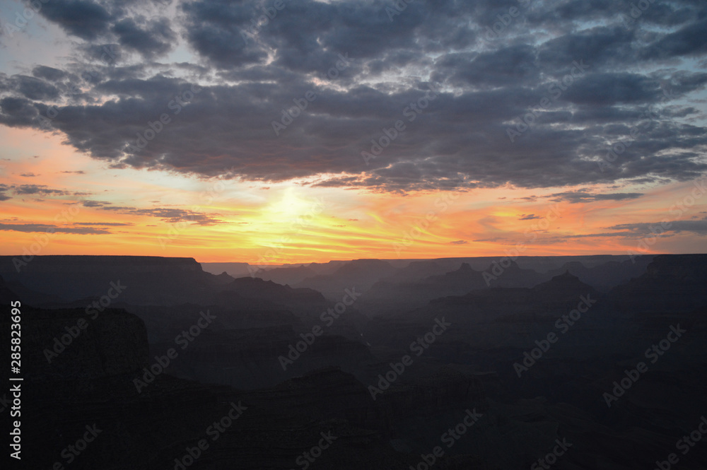 Sunset at the Grand Canyon as the sun is about to slip over the horizon, leaving a beautifully-colored, vibrant sky, gradient mountain ranges