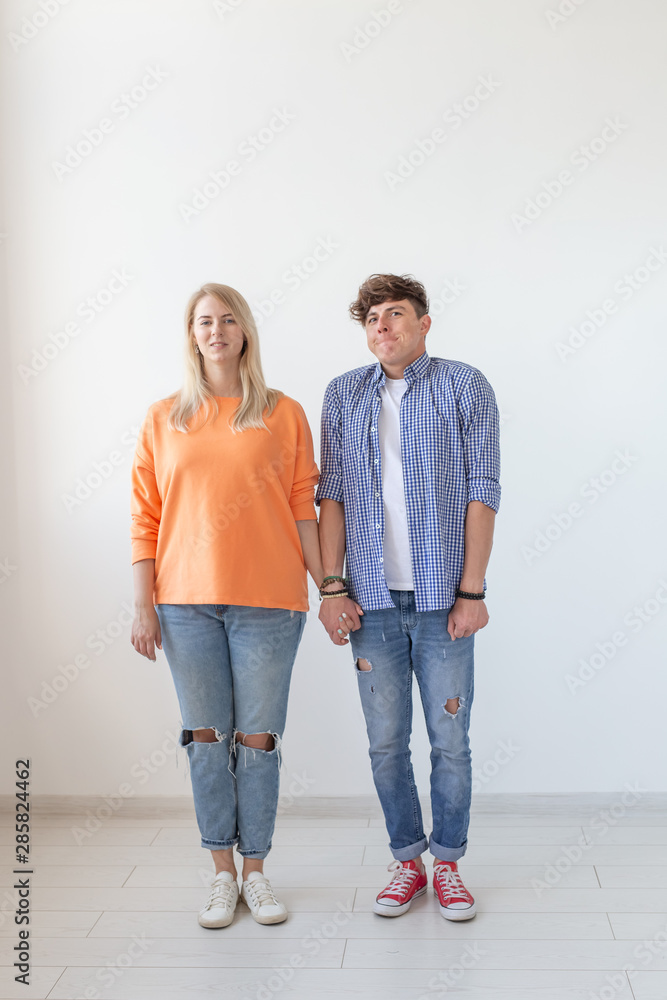 Portrait of a cheerful young positive couple in full growth dressed in casual clothes posing on a white background. Concept of stylish young modern people.
