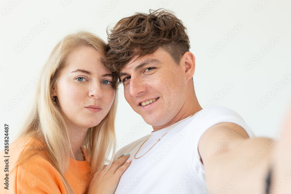 Portrait of a cute positive cheerful young couple of students taking selfie on a smartphone or camera. The concept of a passionate young couple in love with students. Portrait of a cute positive cheerful young couple of students taking selfie on a smartphone or camera. The concept of a passionate young couple in love with students.