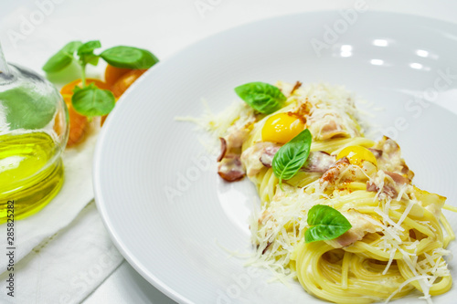 Spaghetti Carbonara with bacon, quail egg, Basil and Parmesan. Spaghetti on white wooden background.