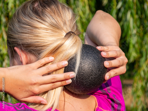 Frau massiert sich mit einer Faszienkugel den Nacken photo