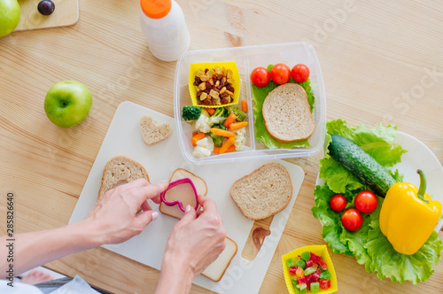 Foto Closeup of female hands preparing sandwich for lunch box