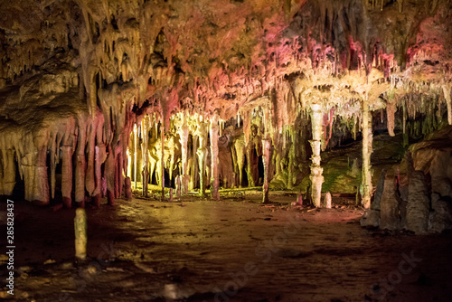 Tableau sur toile Cave dark interior with light, stalactites and stalagmites