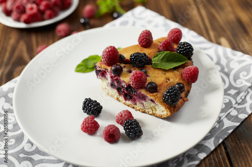Piece of pie with blueberries on a plate, napkin on a wooden boards background