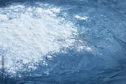 Side view of sprinkled baking wheat flour with shallow depth of field on abstract blue textured background