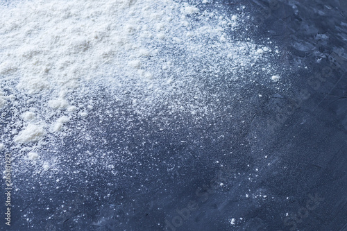 White baking wheat flour sprinkled in the corner of the picture on a dark blue textured grunge background. Shallow depth of field © Andrey_Maksimov