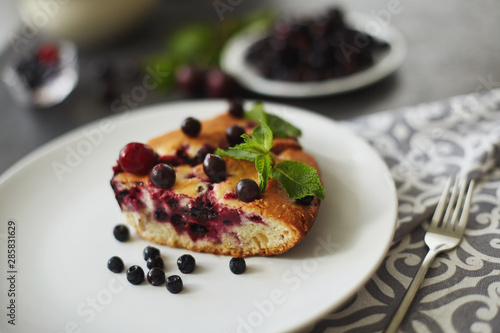 Piece of pie with blueberries, rasberry and mint for dessert on a white plate, napkin. Pieces of delicious homemade cake