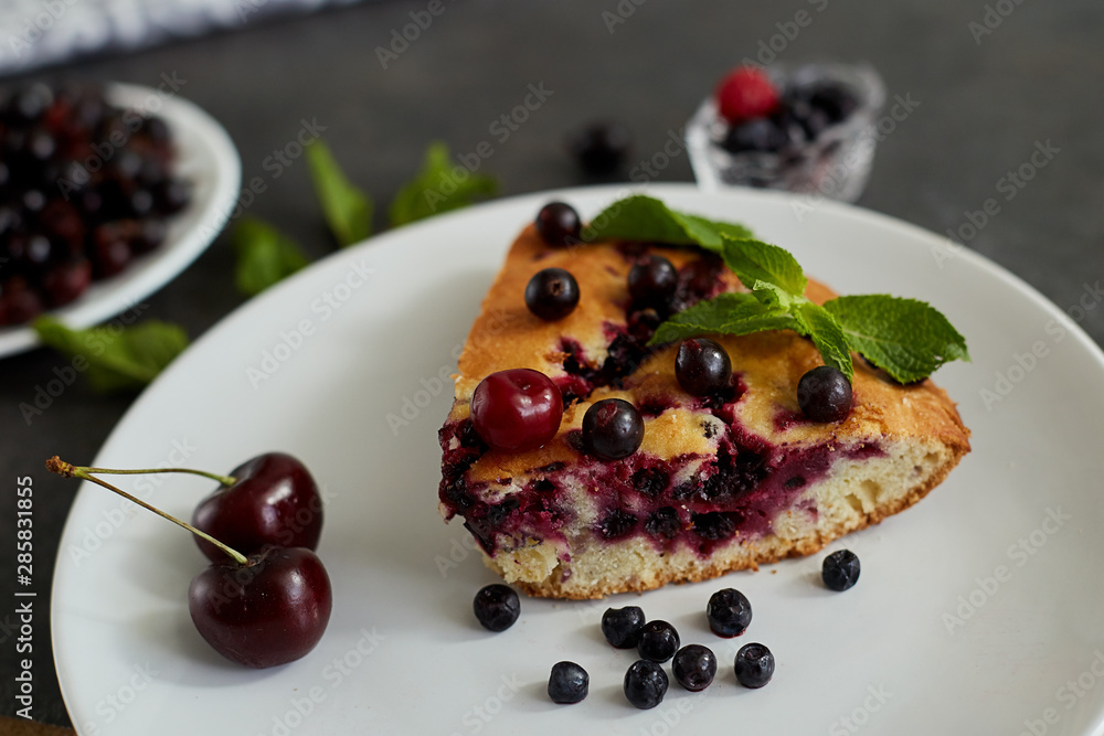 Piece of pie with blueberries, rasberry,cherries and mint for dessert on a white plate, napkin. Pieces of delicious homemade cake
