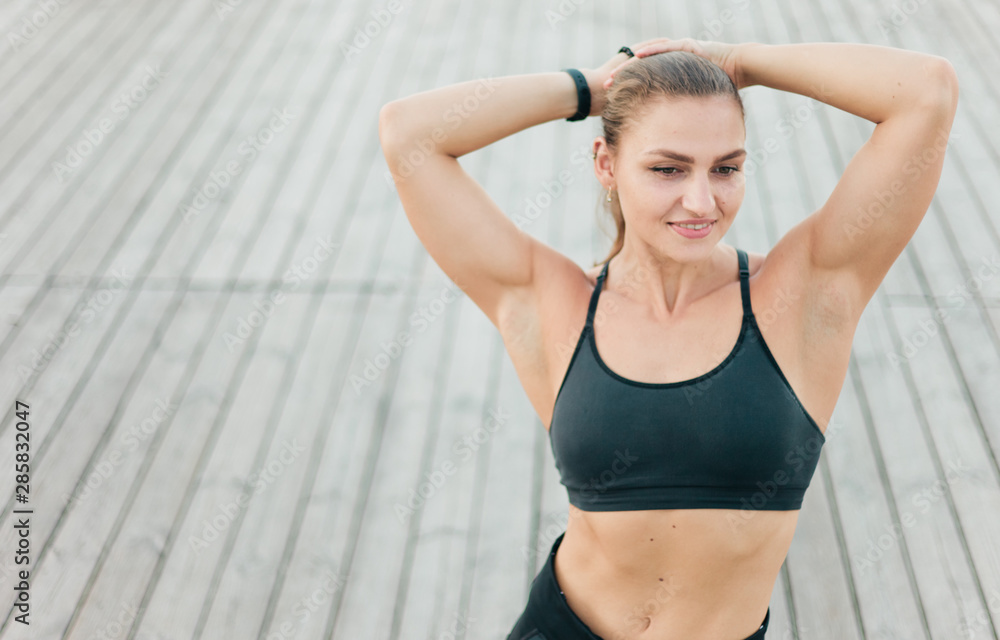 Portrait of pretty caucasian woman in sportswear poses on wooden terrace Portrait of pretty caucasian woman in sportswear poses on wooden terrace