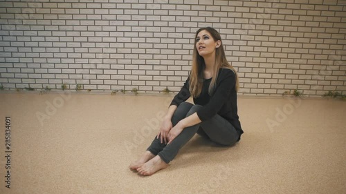 Beautiful girl dancer sits on the floor in the studio Wide angle