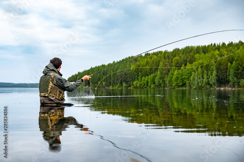 Fisherman using rod fly fishing in river morning standing in water