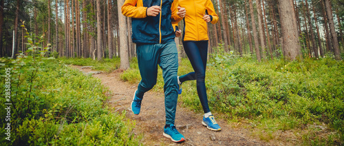 Fototapeta Naklejka Na Ścianę i Meble -  Couple running forest trail. Fitness fast movement stretching training park