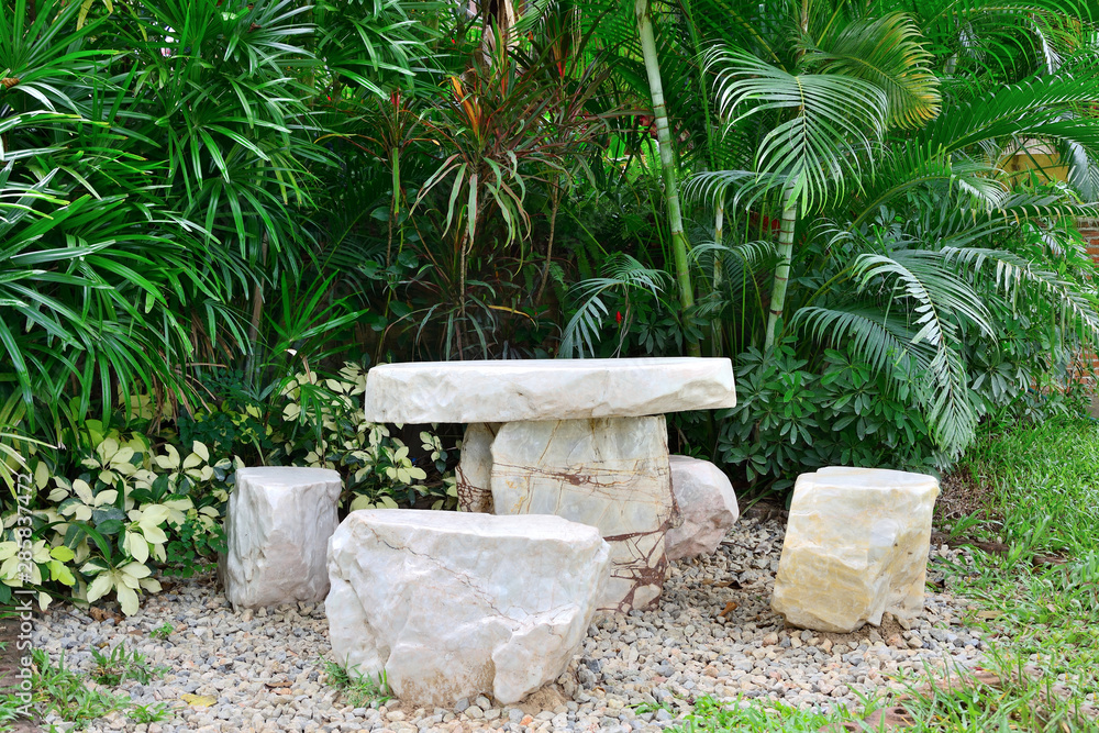 Marble chair on pebbles in garden with tree background. Marble chair on pebbles in garden with tree background.