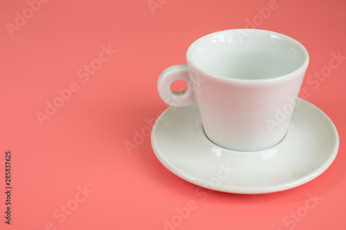 Minimalism white empty Cup with saucer on pink background.