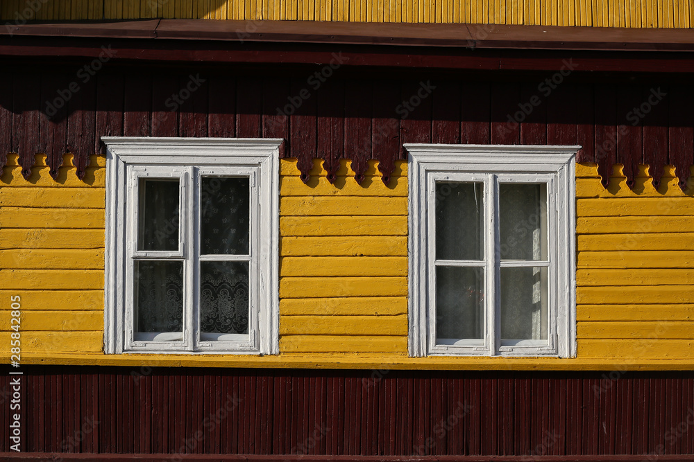 Part of typical house in Lithuania, Trakai. Antique old house with yellow old wood and white windows Part of typical house in Lithuania, Trakai. Antique old house with yellow old wood and white windows