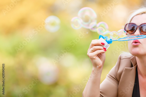 attractive young girl with soap-bubbles in beautiful yellow sunshine
