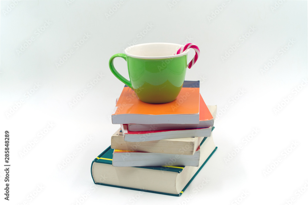 grüne Tasse mit Zuckerstange auf einem Bücherstapel. grüne Tasse mit Zuckerstange auf einem Bücherstapel.