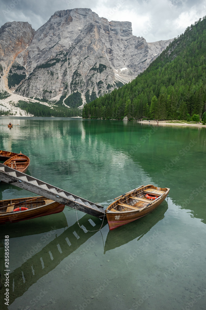 une barque et une passerelle sur un lac vert avec des montagnes en arrière plan