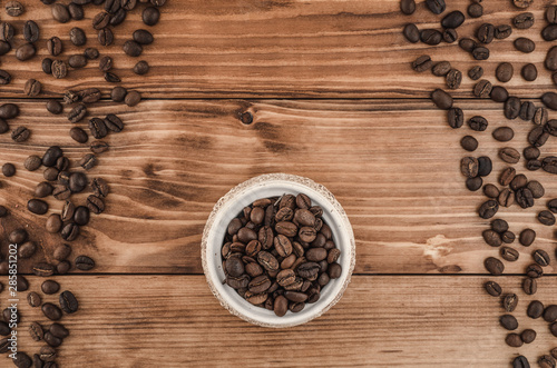 Coffee lines and beens in white pot on brown wooden background. Top view