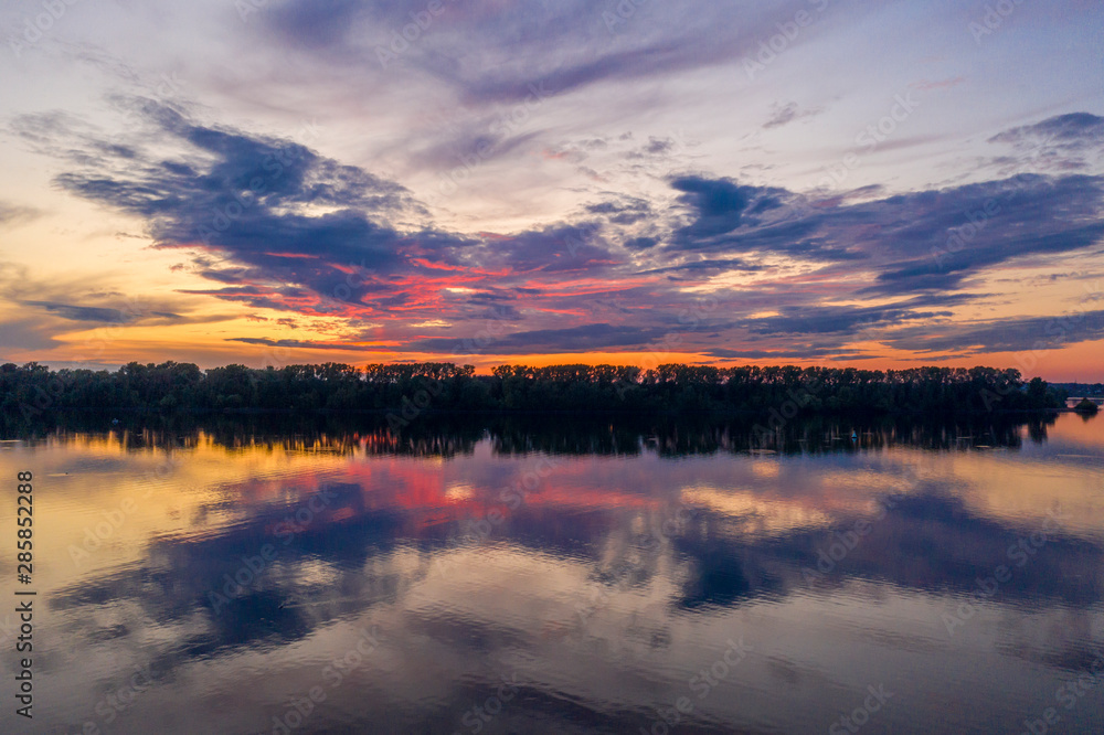 Sunset on the river, clouds in the form of a butterfly illuminated by the violet light of sunset Sunset on the river, clouds in the form of a butterfly illuminated by the violet light of sunset
