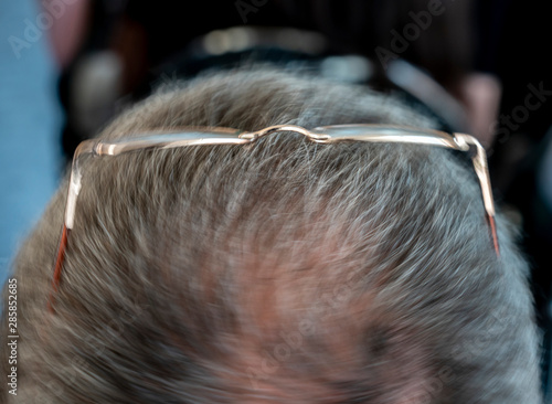 Glasses on the head of a gray-haired man close-up