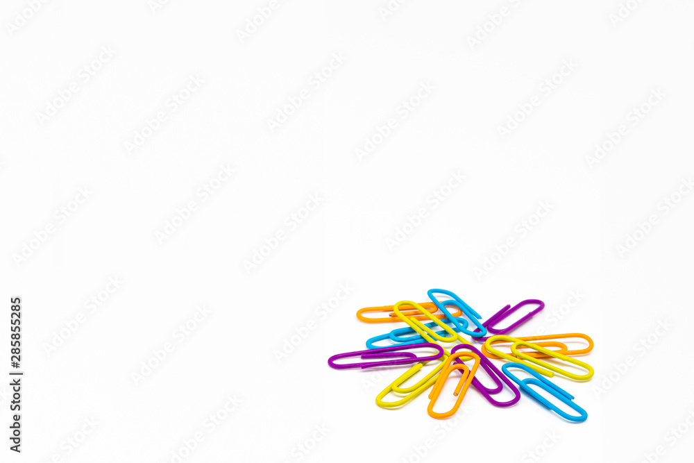 Fototapeta premium Colorful blue-yellow-orange and violet clips on a white table. Back to school