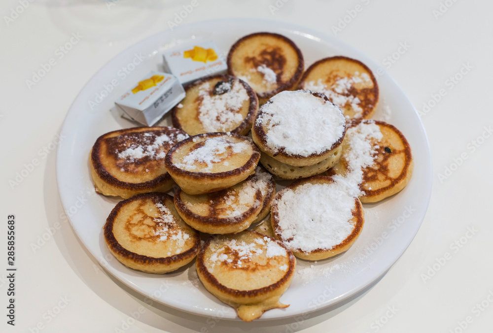Mini Dutch pancakes, Poffertjes, on a white plate, at a cafe in Amsterdam, Netherlands Mini Dutch pancakes, Poffertjes, on a white plate, at a cafe in Amsterdam, Netherlands