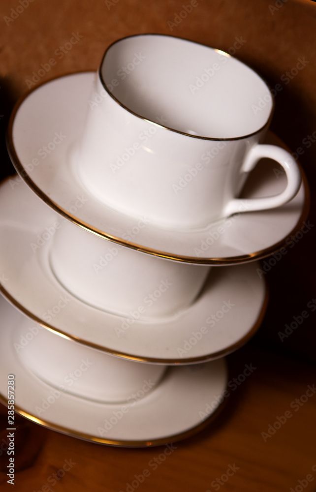 stack of porcelain coffee cups with gold rim on wooden background stack of porcelain coffee cups with gold rim on wooden background