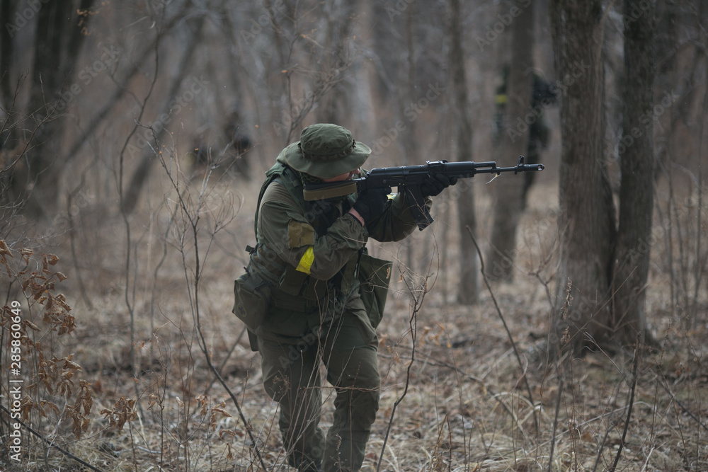 Fototapeta premium Active military exercises in the forest. Shootout army in the autumn forest. Training airsoft teams in Russia.