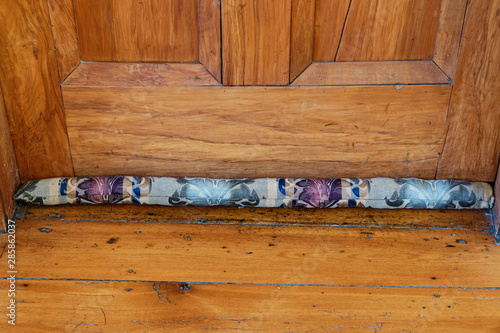 Canvas Print A draught stopper at the base of a wooden door
