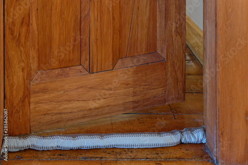 A single draft excluder sits on the floor, the door is open behind it photo