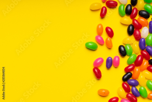 colourful jelly beans candies yellow background Top view 