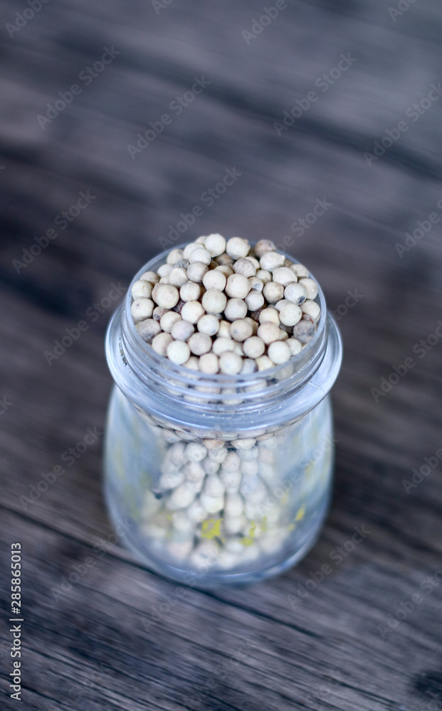 Pepper in a jar on wood background. Pepper in a jar on wood background.
