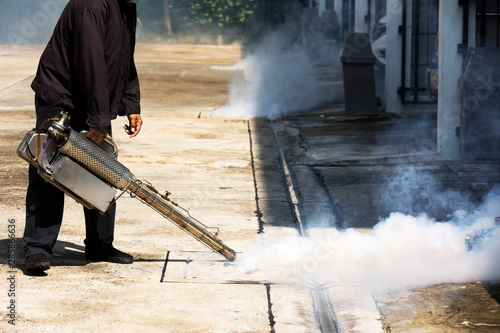 Man pointing smoke machine into manhole for pest control photo