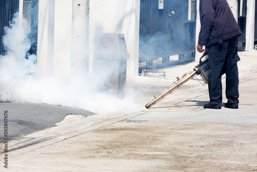 Man pointing smoke machine into manhole for pest control Man pointing smoke machine into manhole for pest control