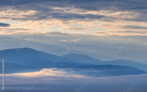 Dawn in the mountains, peaks above the clouds, foggy © Valerii