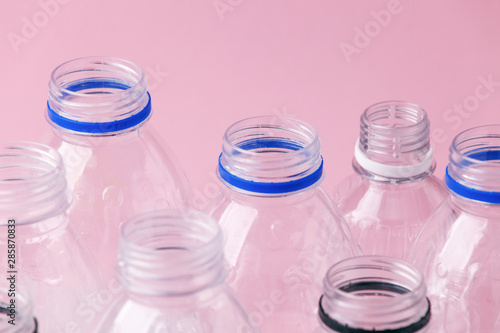 Set of diverse used empty water plastic bottles without caps on pastel pink background. Concept of recycle plastic pakaging, reuse industry, zero waste, eco-friendly