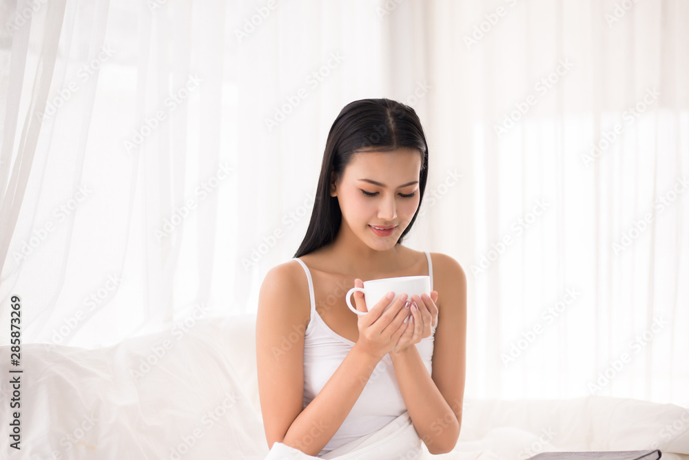 Beautiful asian female holding coffee on bed,Happy and smiling,Positive thinking,Relax time Beautiful asian female holding coffee on bed,Happy and smiling,Positive thinking,Relax time