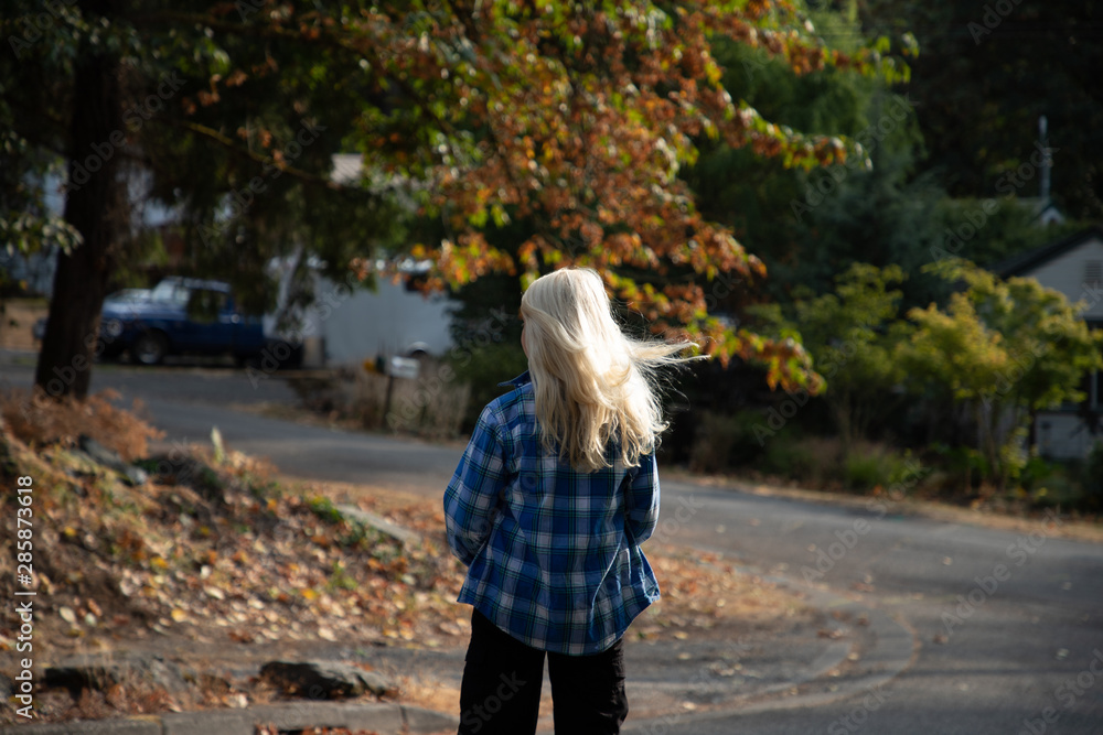 Fototapeta premium 10 year old boy walking down the street with the wind blowing his hair