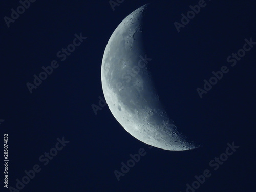 in the blue morning sky stands the waning quarter moon photo