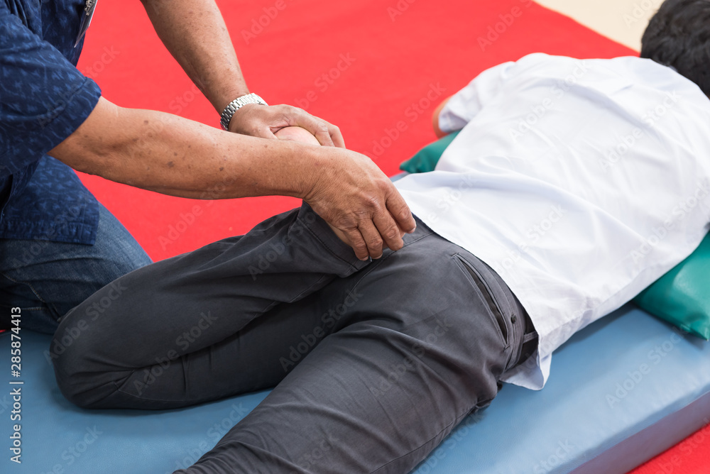 Young working man lying down while enjoying the stretching foot and leg techniques of a professional Thai massage in the spa and wellness center. physical therapy.Muscular treatment office syndrome. Young working man lying down while enjoying the stretching foot and leg techniques of a professional Thai massage in the spa and wellness center. physical therapy.Muscular treatment office syndrome.