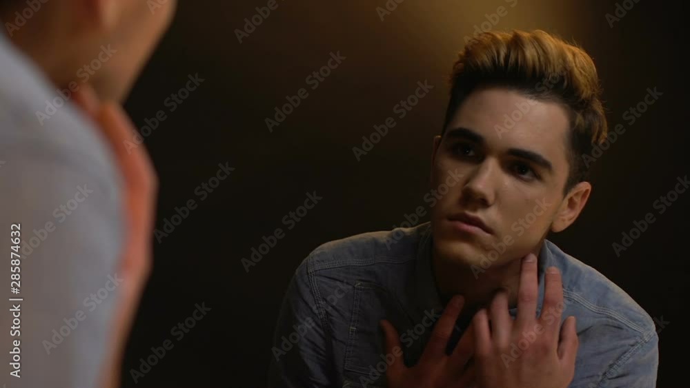 Crying androgynous male looking mirror reflection covering face social exclusion Crying androgynous male looking mirror reflection covering face social exclusion