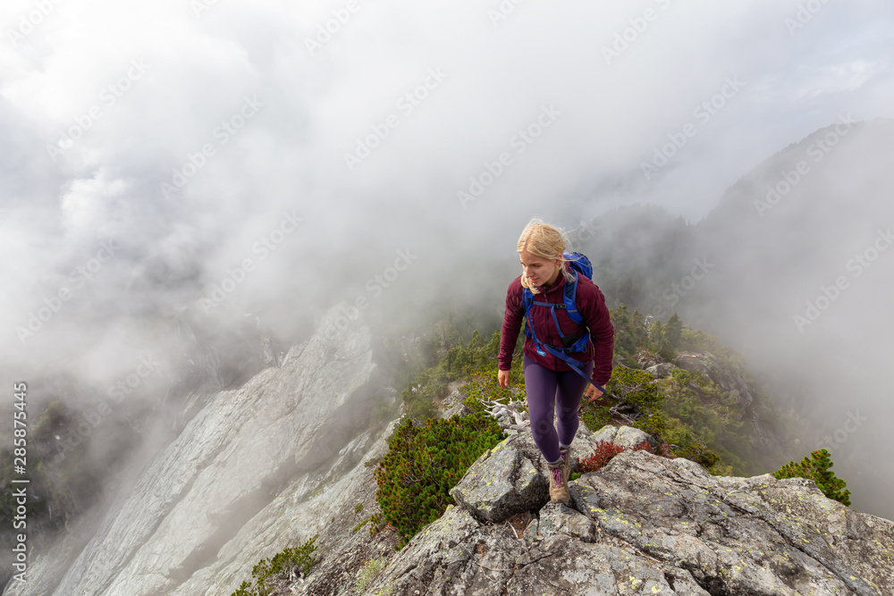 Adventurous Girl is hiking up a steep trail up a beautiful rocky mountain during a cloudy summer morning. Taken on Crown Mountain, North Vancouver, BC, Canada. Adventurous Girl is hiking up a steep trail up a beautiful rocky mountain during a cloudy summer morning. Taken on Crown Mountain, North Vancouver, BC, Canada.