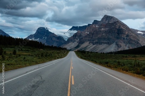 Scenic road in the Canadian Rockies during a vibrant cloudy sunset. Taken in Icefields Parkway, Banff National Park, Alberta, Canada.