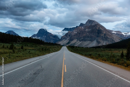 Scenic road in the Canadian Rockies during a vibrant cloudy sunset. Taken in Icefields Parkway, Banff National Park, Alberta, Canada.