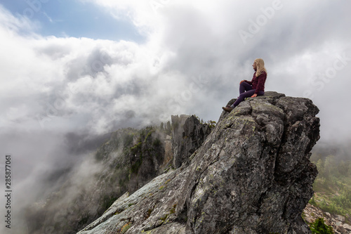 Adventurous Girl on top of a rugged rocky mountain during a cloudy summer morning. Taken on Crown Mountain, North Vancouver, BC, Canada. © edb3_16