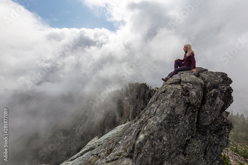 Adventurous Girl on top of a rugged rocky mountain during a cloudy summer morning. Taken on Crown Mountain  North Vancouver  BC  Canada.